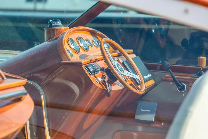 Slide: The Image of Interior of a 2003 Hinckley Talaria 29R boat, featuring a classic wooden dashboard and steering wheel. - 25