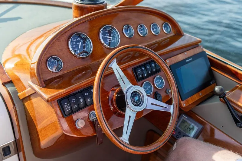 Slide: The Image of Steering wheel and dashboard of a 2003 Hinckley Talaria 29R boat, featuring wood finish and gauges. - 28