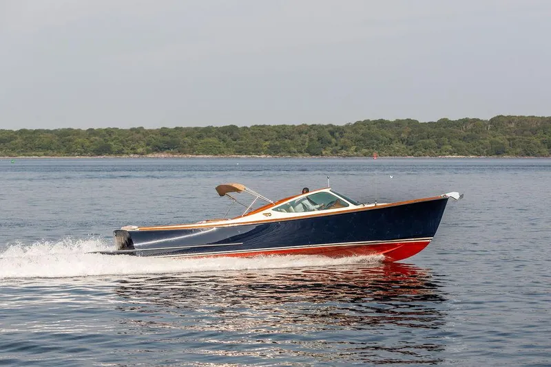 Slide: The Image of 2003 Hinckley Talaria 29R cruising on calm waters near a forested shoreline. - 5