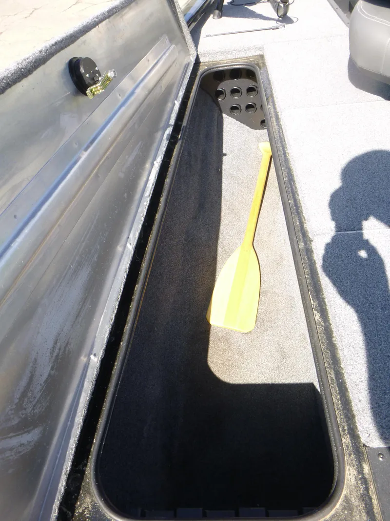 Slide: The Image of 2023 Tracker Pro Team 195 TXW Tournament Edition boat storage compartment with a yellow paddle. - 10