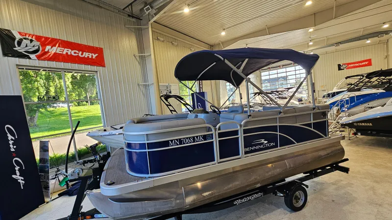 Slide: The Image of 2020 Bennington 188 SV pontoon boat displayed in a showroom with Mercury signage. - 4