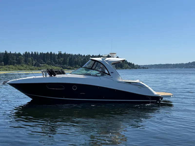 Slide: The Image of 2012 Sea Ray 370 Sundancer yacht cruising on a serene lake under clear blue skies. - 0