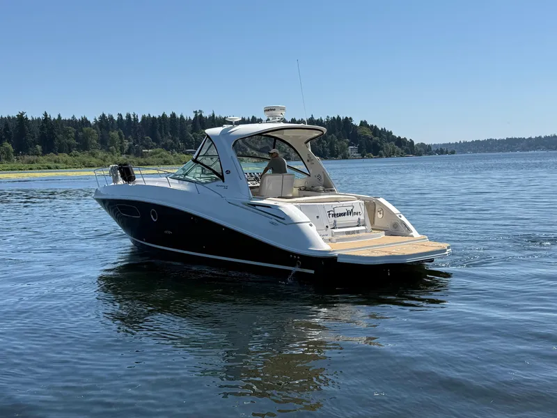 Slide: The Image of 2012 Sea Ray 370 Sundancer cruising on a serene lake under a clear blue sky. - 2