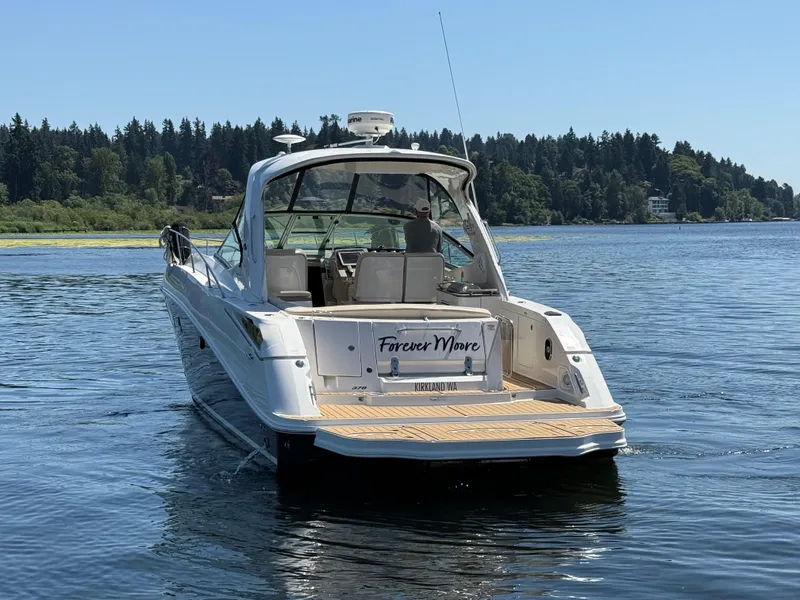 Slide: The Image of 2012 Sea Ray 370 Sundancer boat on a serene lake with forested shoreline. - 3