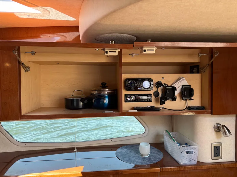 Slide: The Image of Interior of 2012 Sea Ray 370 Sundancer with open cabinet, cookware, and audio equipment. - 48