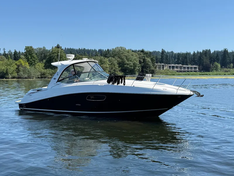 Slide: The Image of 2012 Sea Ray 370 Sundancer yacht on a serene lake with lush greenery. - 7