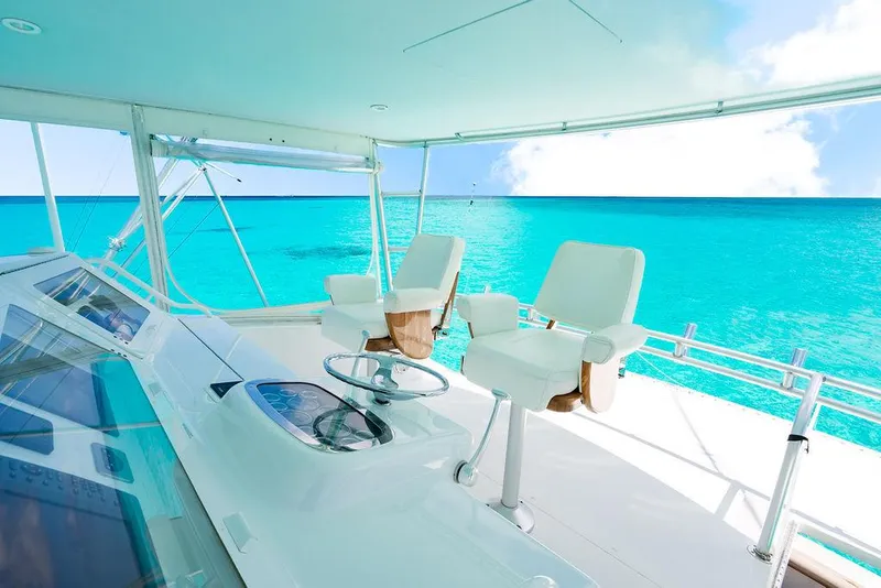 Slide: The Image of 1999 Viking Convertible yacht helm with ocean view, featuring white captain chairs and steering wheel. - 10