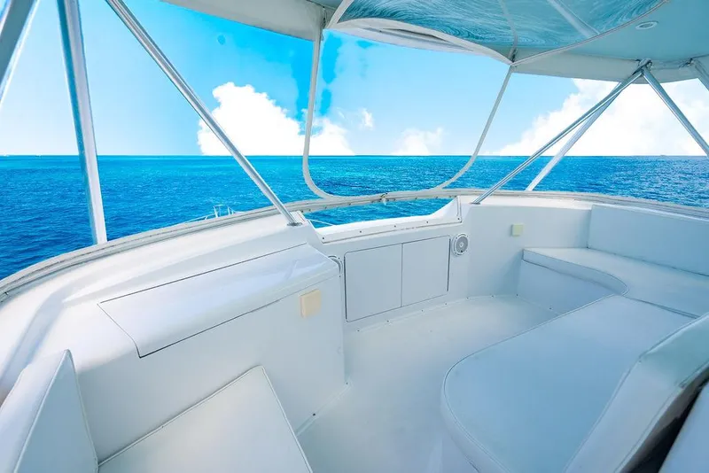 Slide: The Image of 1999 Viking Convertible yacht interior with ocean view, featuring white seating and clear blue skies. - 33