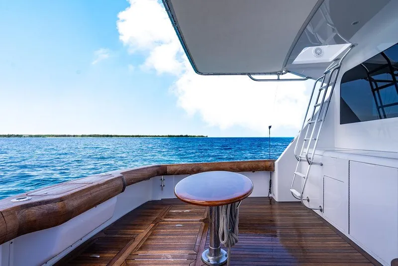 Slide: The Image of 1999 Viking Convertible yacht deck with ocean view, featuring wooden flooring and a ladder. - 35