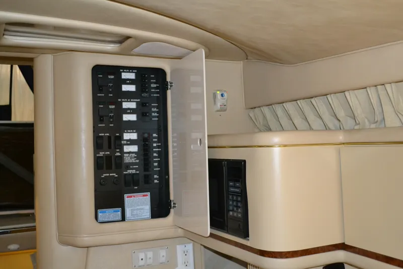 Slide: The Image of 1998 Sea Ray 330 Sundancer interior with open electrical panel and beige cabinetry. - 11