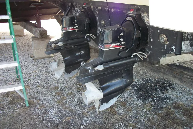 Slide: The Image of Twin Mercury outboard motors on a 2001 Thompson 3400 Santa Cruz boat, resting on gravel. - 6