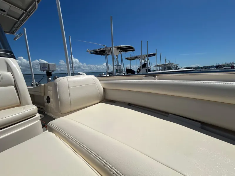 Slide: The Image of 2019 Grady-White Fisherman 236 boat interior with beige seating, docked under clear blue sky. - 25