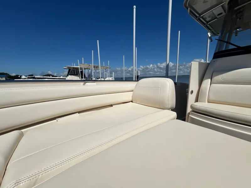 Slide: The Image of 2019 Grady-White Fisherman 236 boat interior with beige seating, docked under clear blue sky. - 26