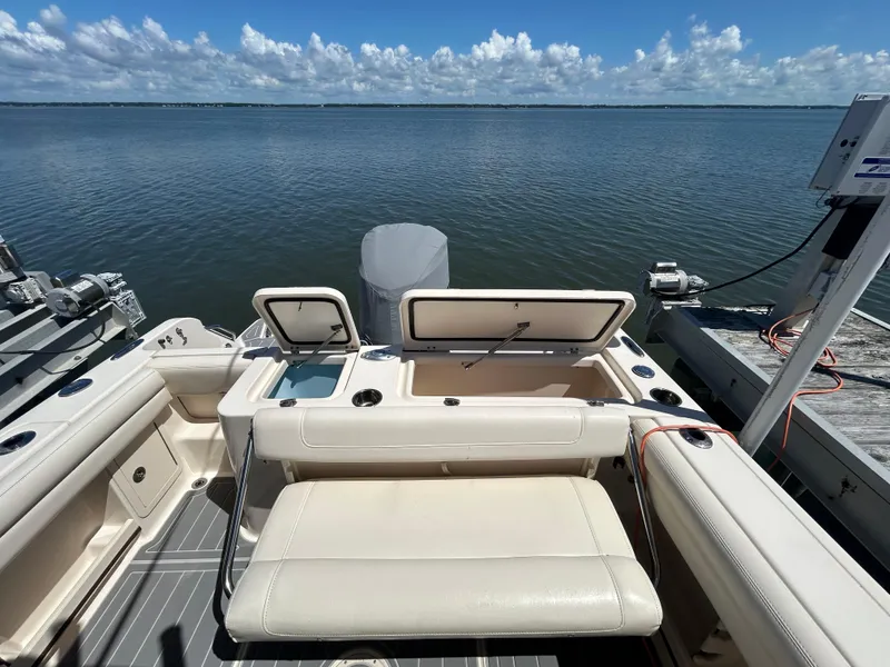 Slide: The Image of 2019 Grady-White Fisherman 236 boat interior with open storage compartments, docked by calm waters. - 6