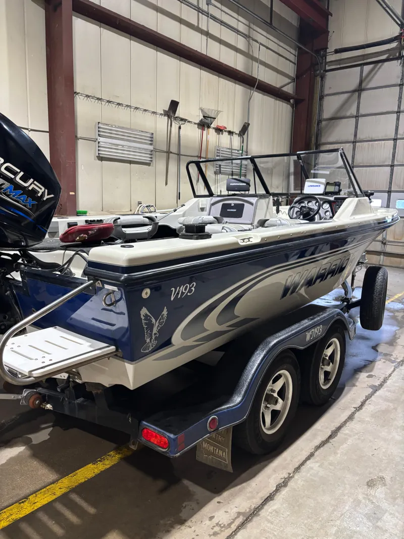 Slide: The Image of 1999 Warrior V193 boat in a garage, on a trailer, with Mercury engine. - 2