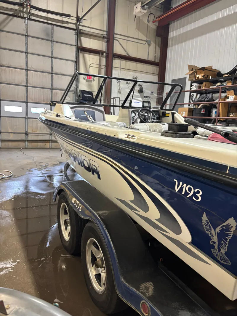 Slide: The Image of 1999 Warrior V193 boat in garage, blue and white design, on trailer. - 3