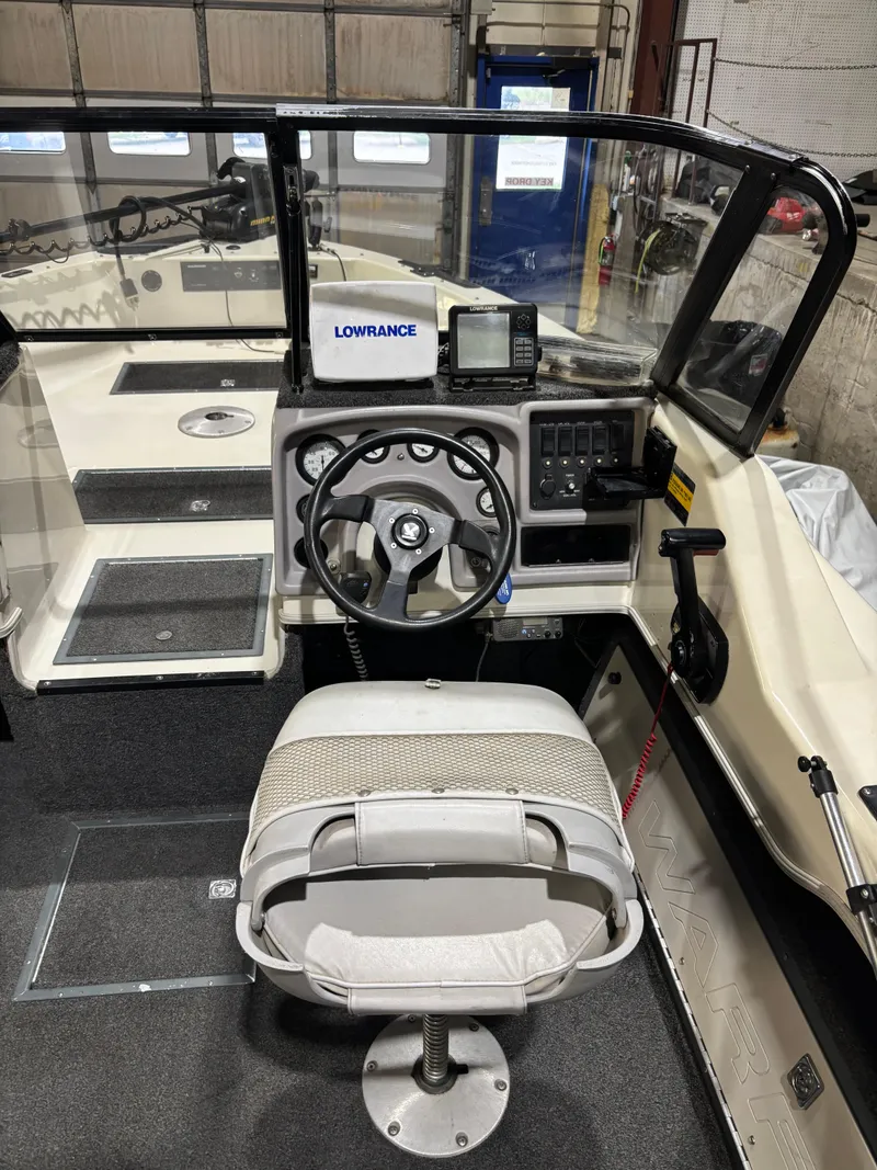 Slide: The Image of 1999 Warrior V193 boat cockpit with steering wheel, Lowrance equipment, and cushioned seat. - 6