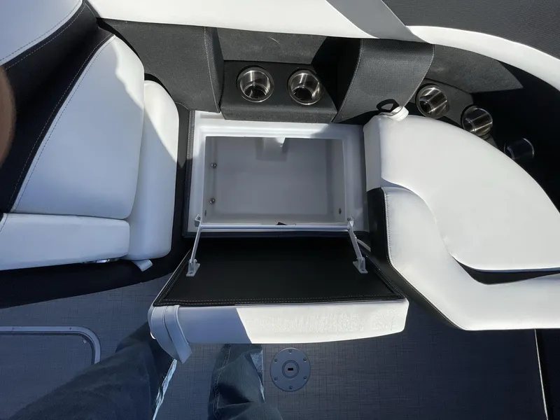 Slide: The Image of 2025 South Bay S224RS boat interior with open storage compartment and cup holders. - 26