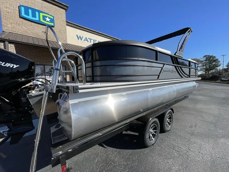 Slide: The Image of 2025 South Bay S224RS pontoon boat on trailer, parked outside dealership. - 6