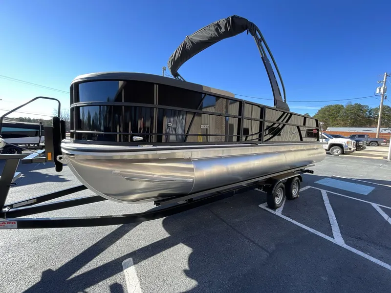 Slide: The Image of 2025 South Bay S224RS pontoon boat on trailer under clear blue sky. - 2