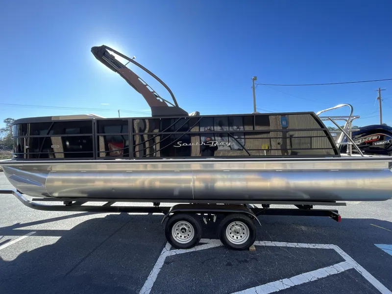 Slide: The Image of 2025 South Bay S224RS pontoon boat on trailer under clear blue sky. - 3
