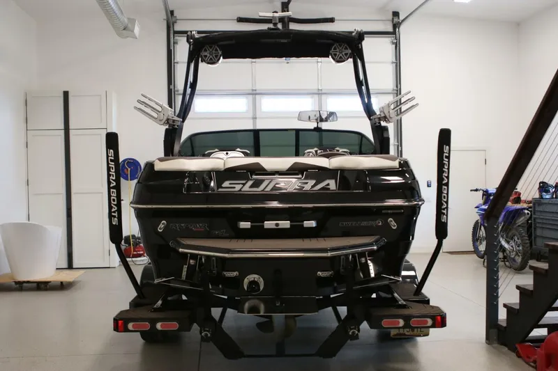 Slide: The Image of 2018 Supra SR400 boat in garage, rear view with wakeboard tower and equipment. - 52