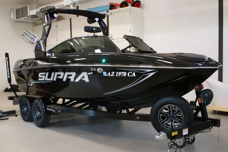 Slide: The Image of 2018 Supra SR400 boat on trailer in garage, sleek black design. - 7