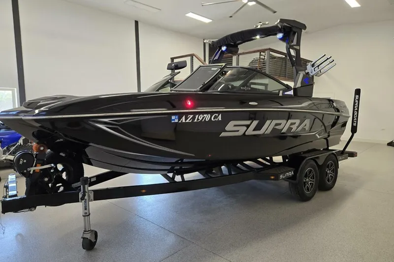 Slide: The Image of 2018 Supra SR400 boat on trailer in a garage, sleek black design. - 2