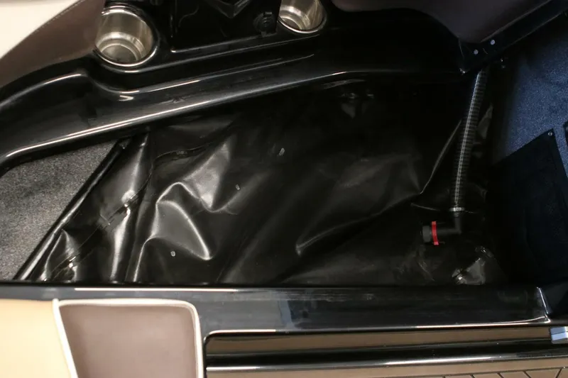 Slide: The Image of Interior storage compartment of a 2018 Supra SR400 boat, featuring cup holders and black lining. - 79