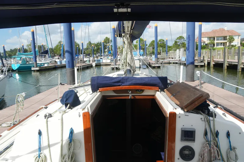 Slide: The Image of 1985 Pearson 303 sailboat docked at marina, view from cockpit, clear sky, calm water. - 12