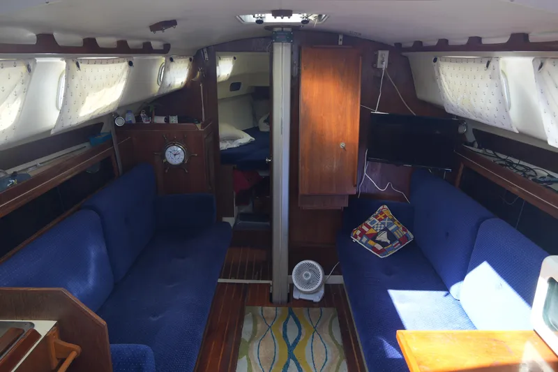 Slide: The Image of Interior of 1985 Pearson 303 sailboat with blue seating and wooden cabinetry. - 14
