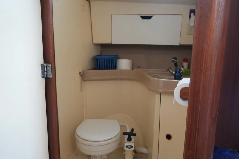 Slide: The Image of Compact bathroom inside a 1985 Pearson 303 sailboat, featuring a toilet and sink. - 20