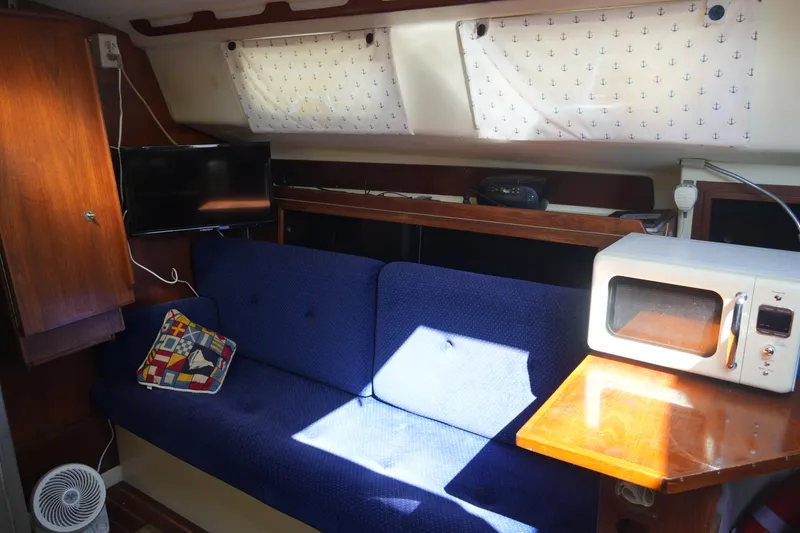Slide: The Image of Interior of 1985 Pearson 303 sailboat with blue sofa, microwave, and TV. - 22