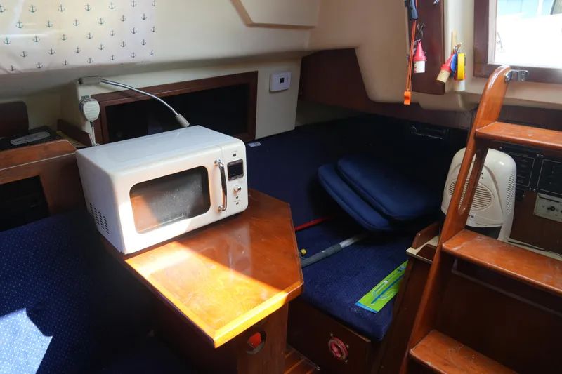 Slide: The Image of Cozy interior of a 1985 Pearson 303 sailboat with microwave and seating area. - 26
