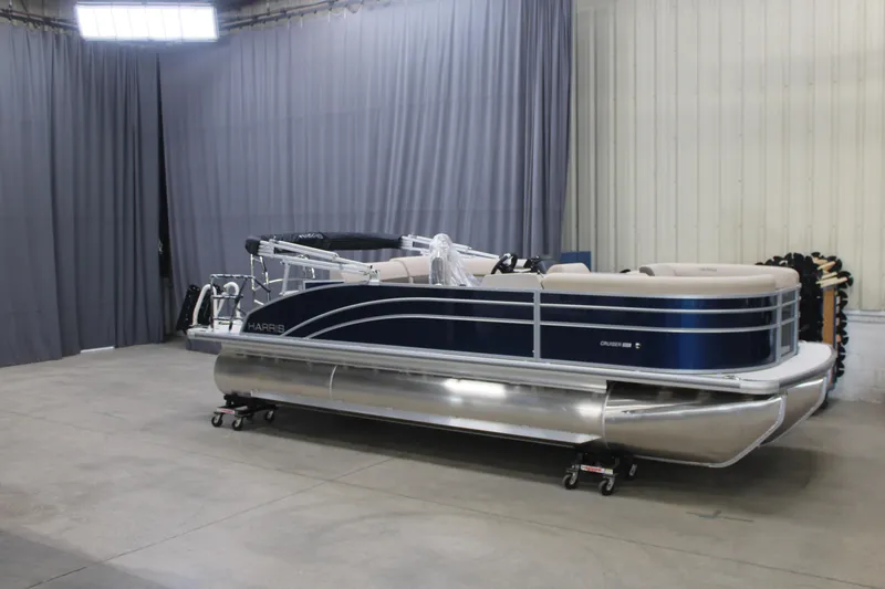 Slide: The Image of 2026 Harris Cruiser 210 pontoon boat in a showroom with gray curtains. - 7