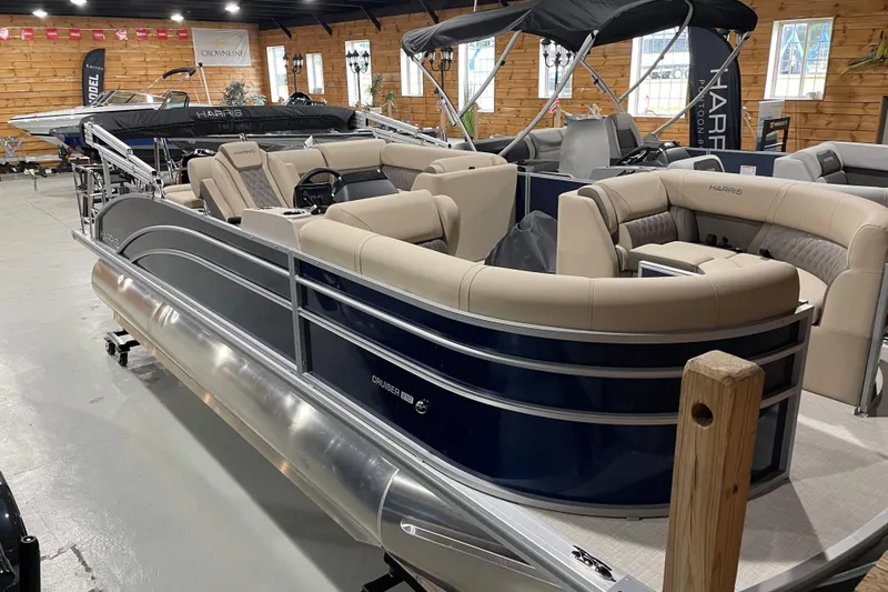 Slide: The Image of 2026 Harris Cruiser 210 pontoon boat with beige seating in a showroom. - 9
