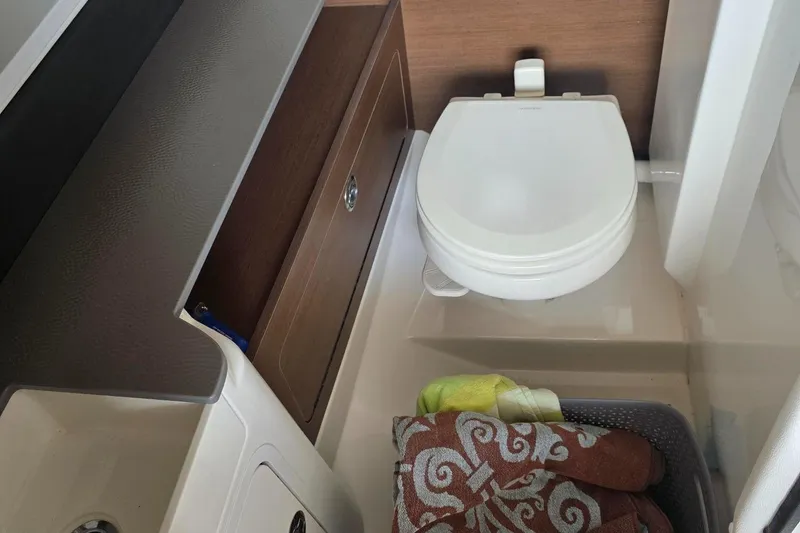 Slide: The Image of 2019 Sea Ray SDX 290 boat bathroom with toilet, towels, and storage cabinet. - 15