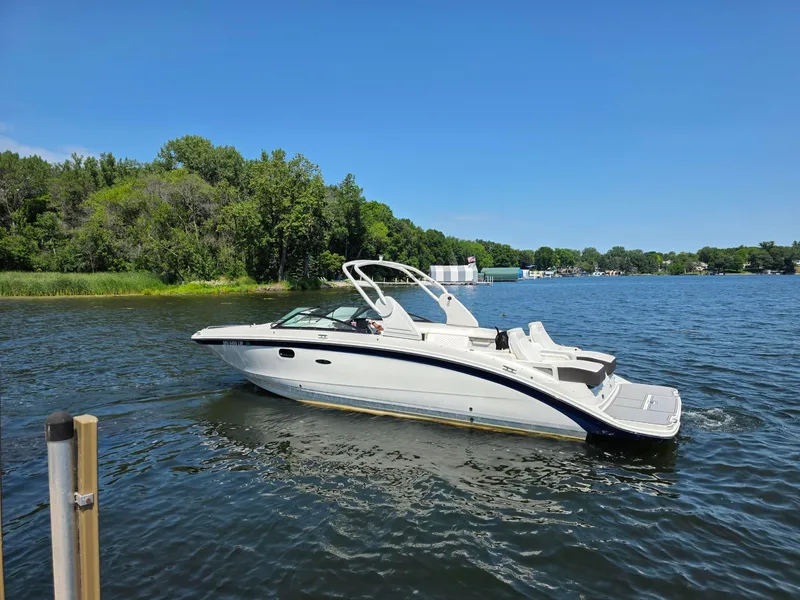 Slide: The Image of 2019 Sea Ray SDX 290 boat cruising on a serene lake under a clear blue sky. - 2