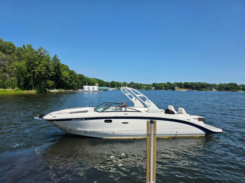 Slide: The Image of 2019 Sea Ray SDX 290 boat cruising on a sunny lake with lush green shoreline. - 4