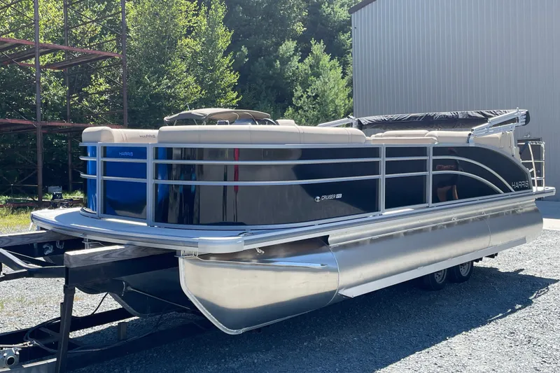 Slide: The Image of 2026 Harris Cruiser 210 pontoon boat on trailer, parked outdoors near a building. - 4