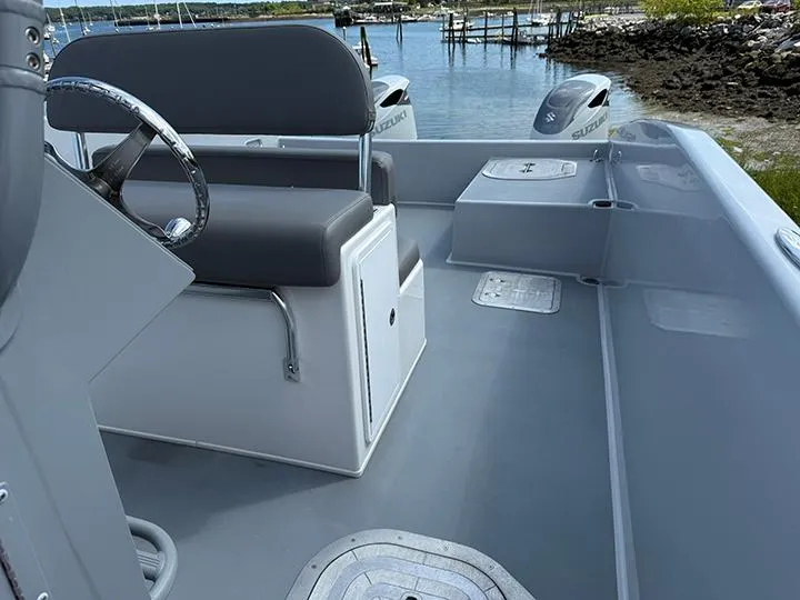Slide: The Image of Custom T-33 PATROL boat interior with steering wheel, seating, and Suzuki engines, dockside view. - 4