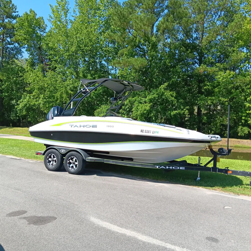 Slide: The Image of Tahoe 1950 boat on trailer, parked on roadside, surrounded by lush green trees. - 2