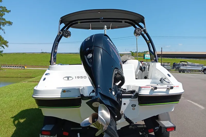 Slide: The Image of Tahoe 1950 boat, 2017 model, with outboard motor, parked on grass under clear blue sky. - 3