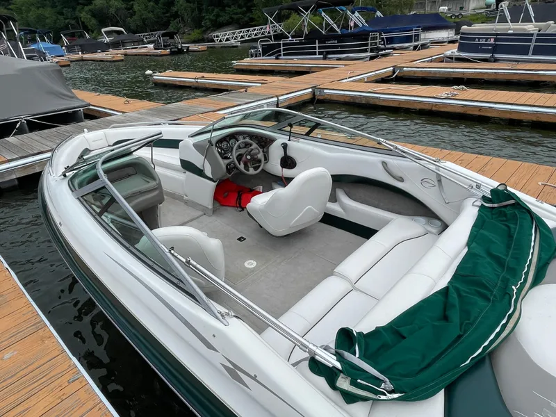 Slide: The Image of 2001 Crownline 202 BR boat docked, featuring white and green interior, steering wheel, and seating. - 4