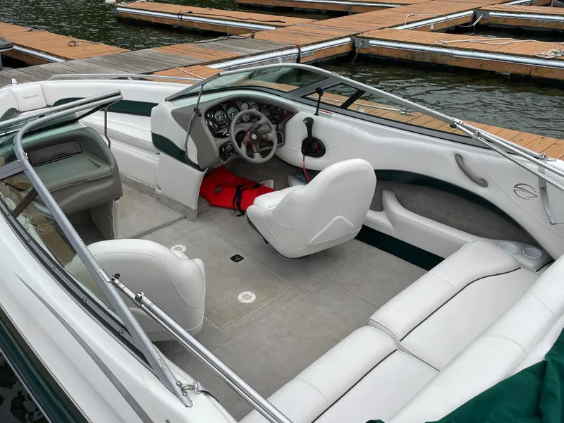 Slide: The Image of 2001 Crownline 202 BR boat interior with white seating, docked at a marina. - 5