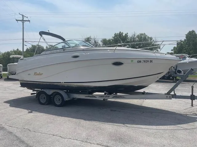 Slide: The Image of 2002 Rinker 250 FV boat on trailer, parked outdoors on a sunny day. - 4