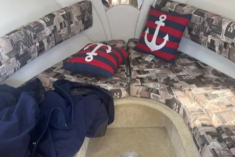 Slide: The Image of Interior of a 2002 Rinker 250 FV boat with nautical-themed cushions. - 5