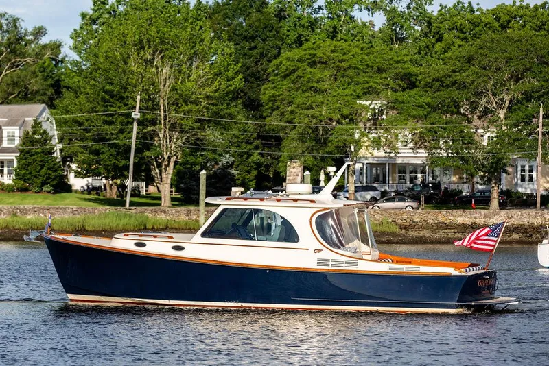 Slide: The Image of 2011 Hinckley Picnic Boat Mark III cruising on a scenic river with lush greenery. - 13