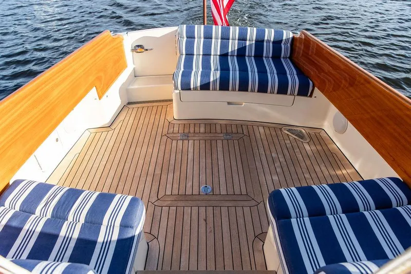 Slide: The Image of 2011 Hinckley Picnic Boat Mark III with striped seating and wooden deck on water. - 32