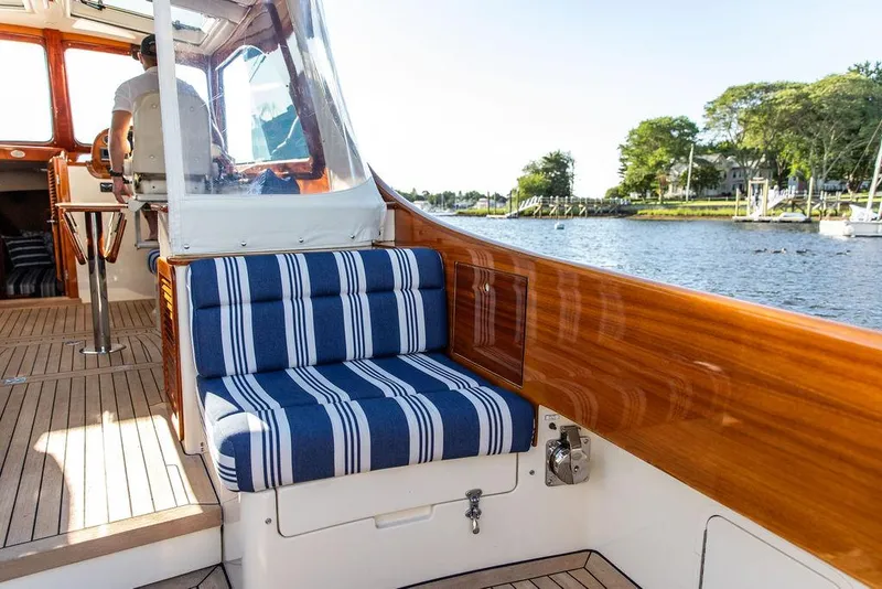 Slide: The Image of 2011 Hinckley Picnic Boat Mark III interior with striped seating, wooden finish, and scenic water view. - 40